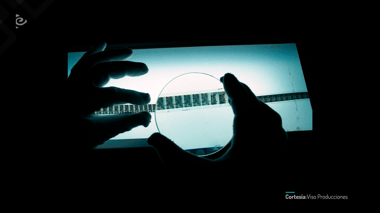 P.P. de las manos de una persona observando una película fílmica.