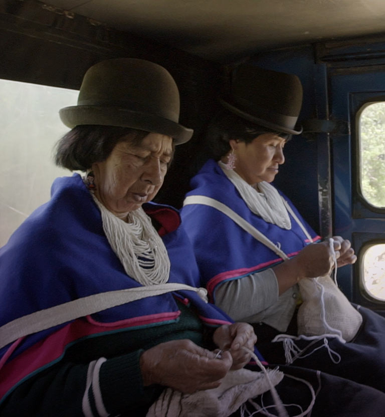 dos mujeres indígenas adultas mayores tejiendo y vistiendo trajes típicos