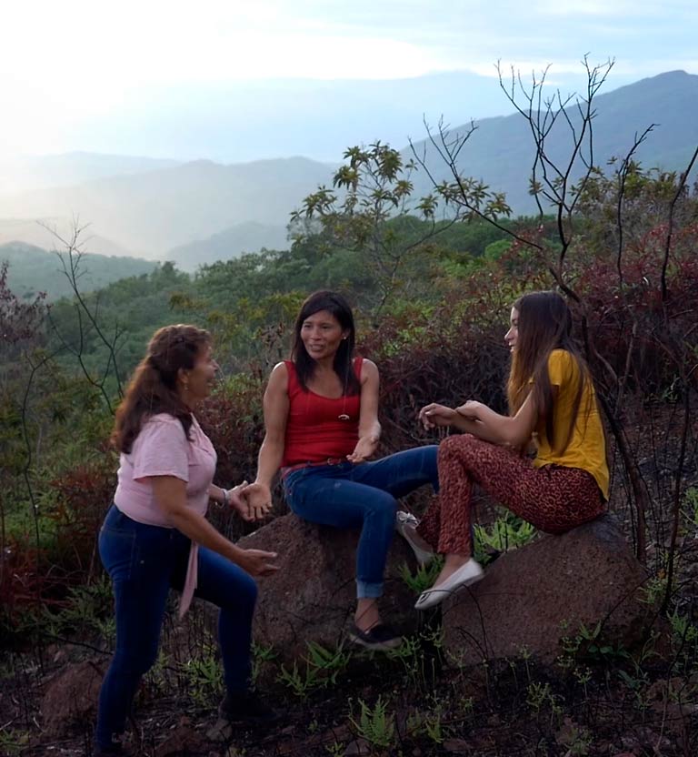 Tres mujeres jóvenes hablando en una montaña - Margures Managrande’