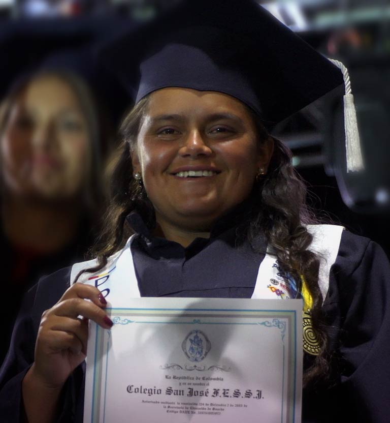 niña adolescente sonriendo con toga y birrete sosteniendo un diploma 