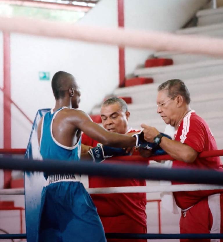 Joven afro junto a sus entrenadores en el ring de boxeo - Nocaut