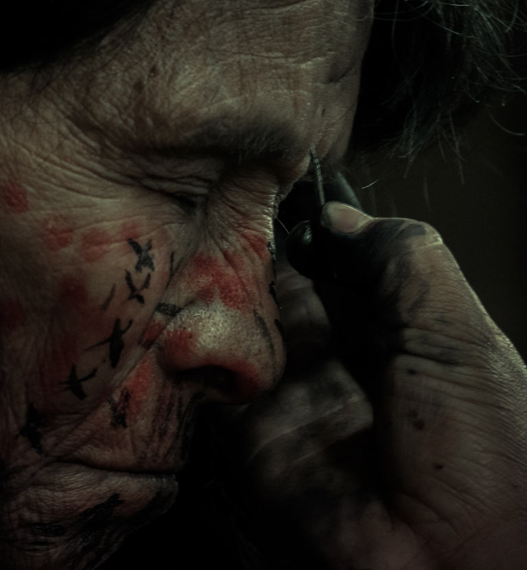 adulto mayor indígena pintándose la cara 