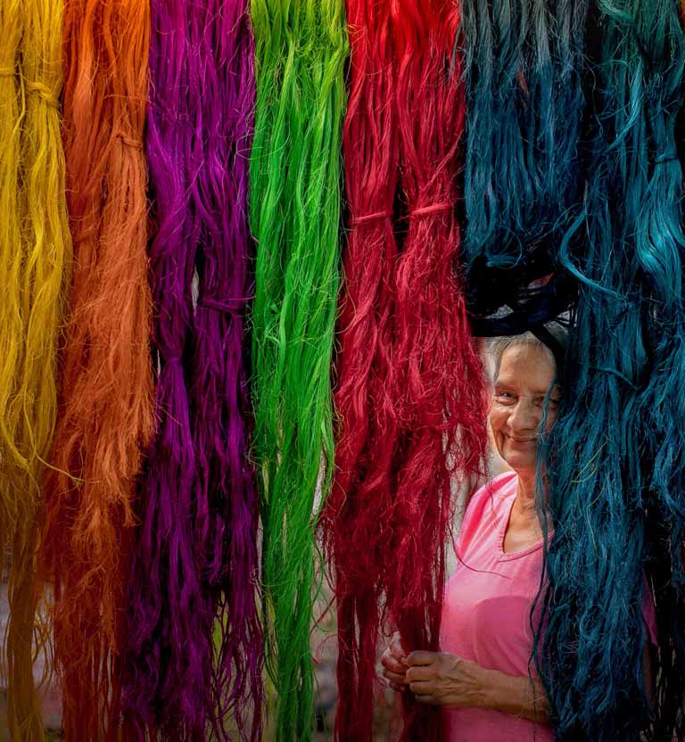 adulta mayor sonriendo entre fique de colores