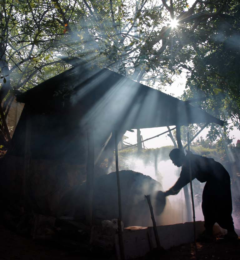 Hombre tratando de prender una hoguera debajo de una carpa