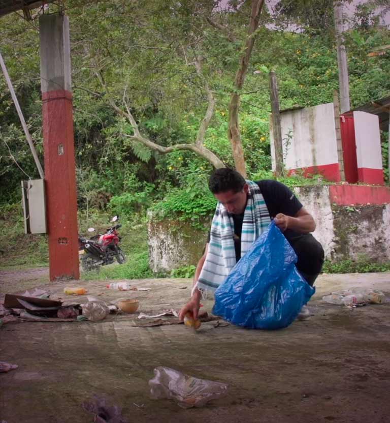 Hombre recogiendo basura en una zona rural - Tan cerca y tan lejos