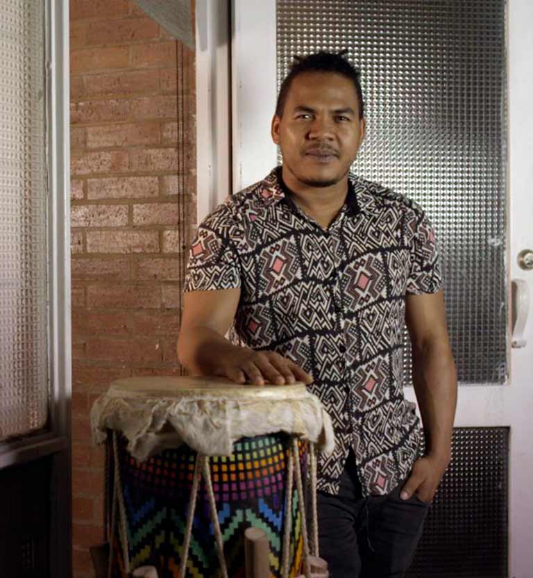 Hombre afro con su mano encima de un tambor 