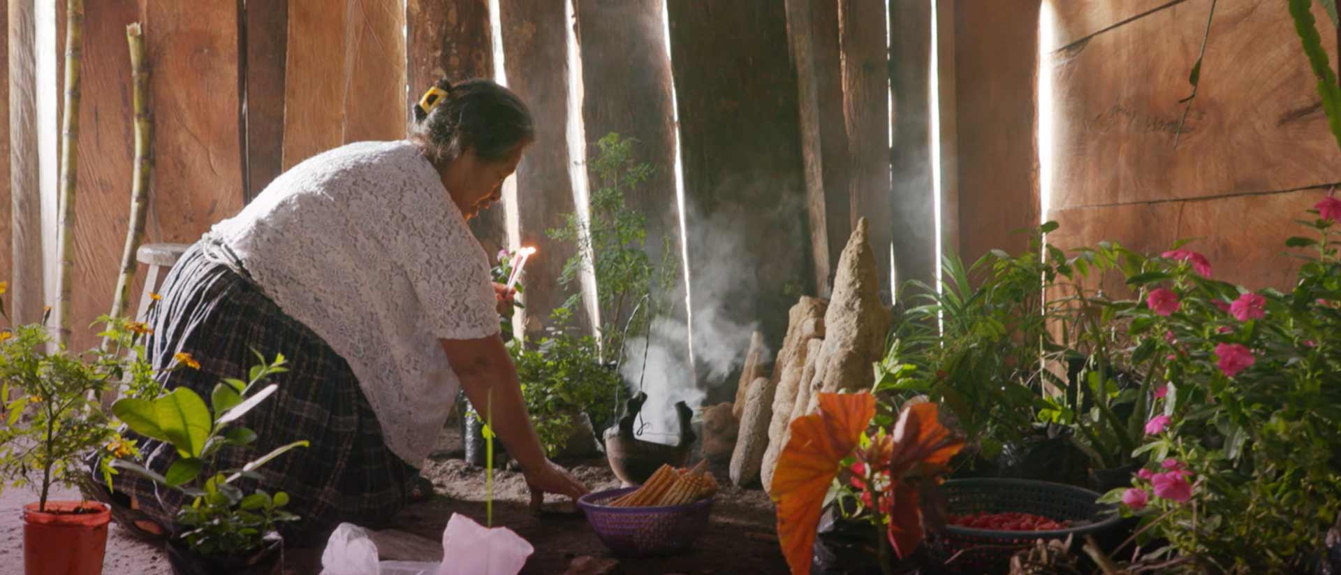 Mujer mayor poniendo unas velas para un rito ceremonial.