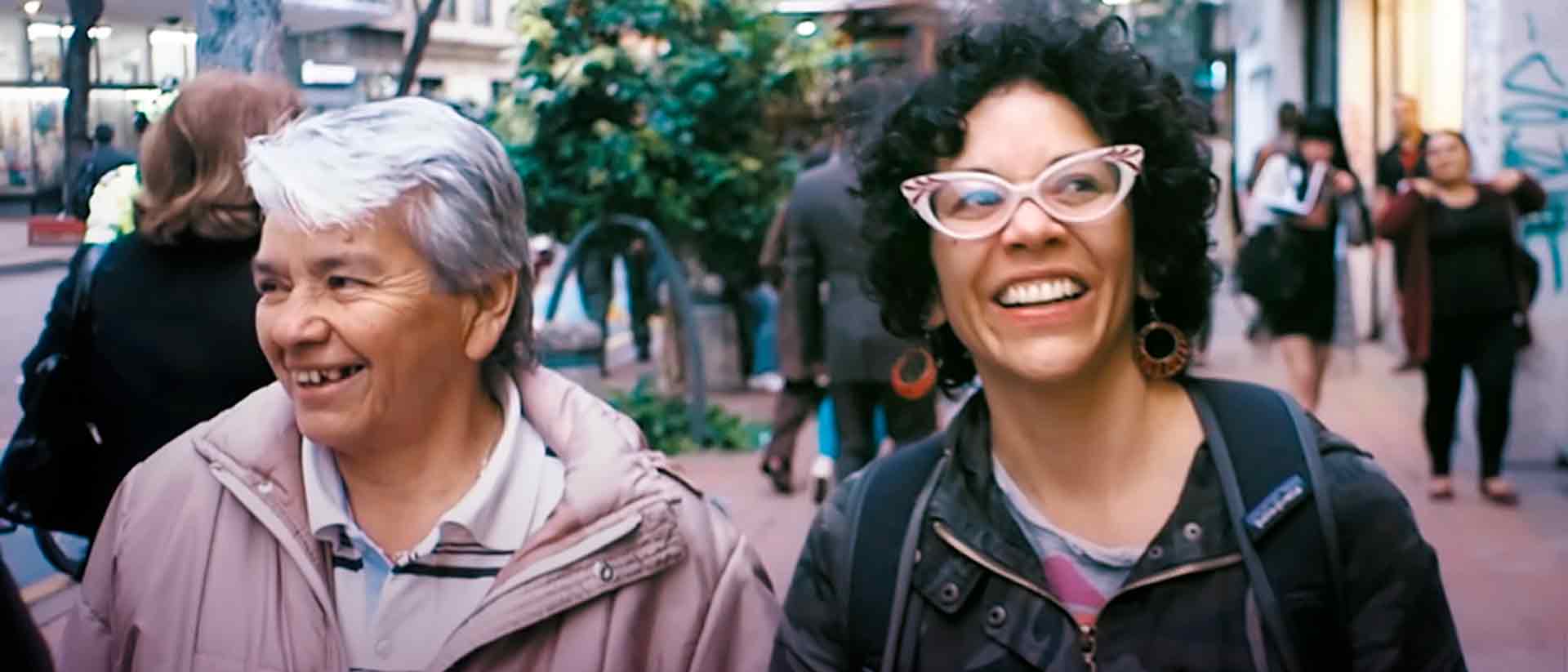 Mujer anciana y mujer joven sonriendo y caminando por las calles de la ciudad - Clara