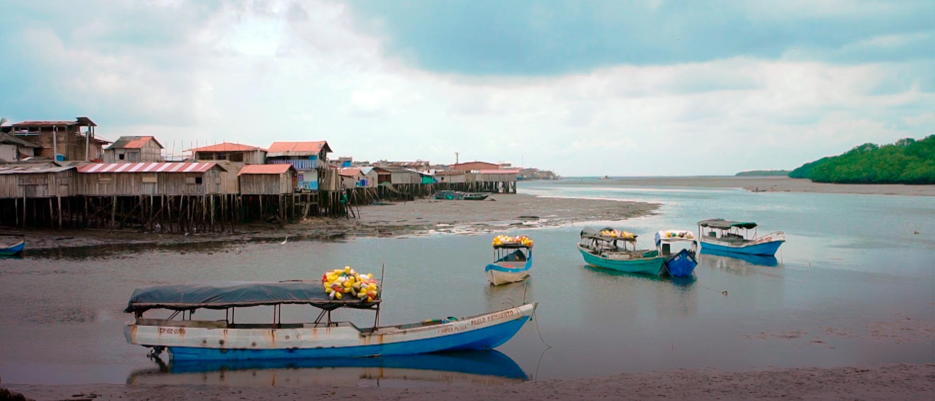 Lanchas en entrada del mar en Tumaco, al fondo casas en madera.