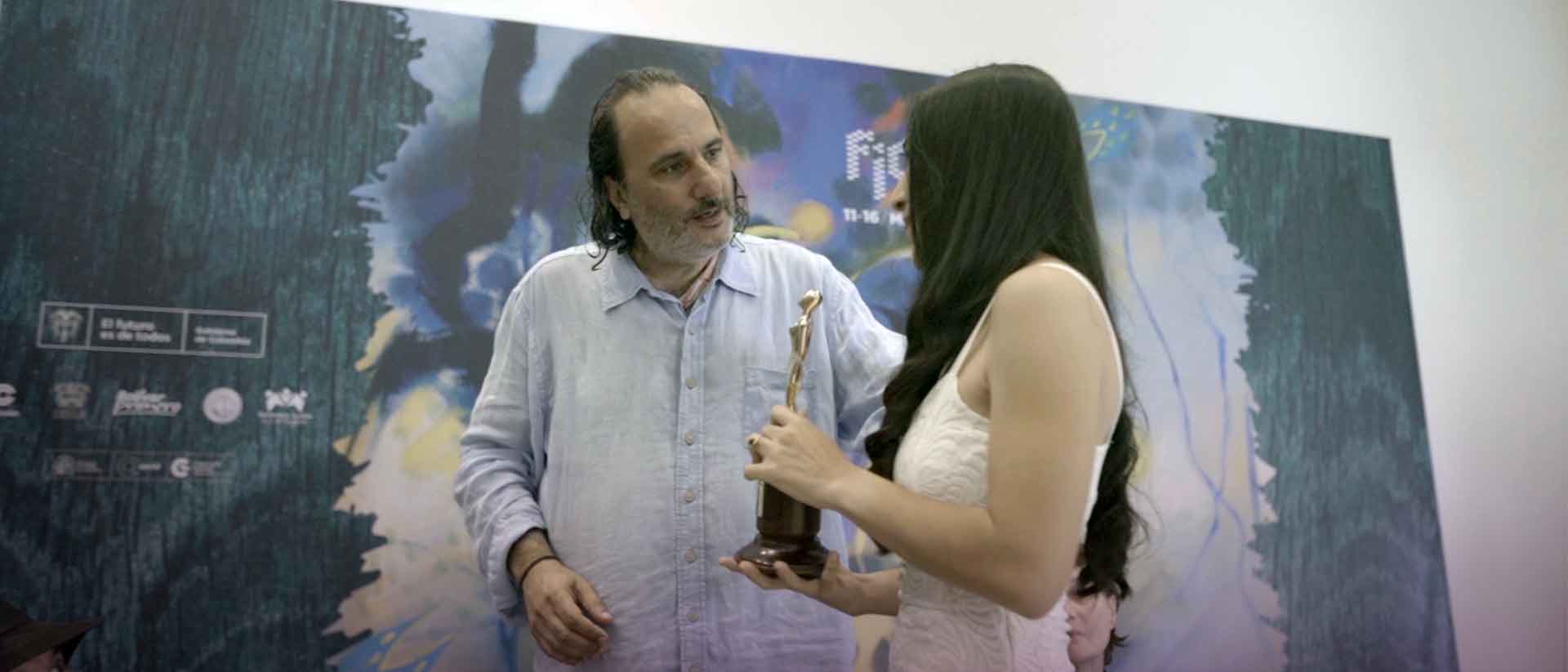 hombre y mujer adultos conversando y sosteniendo un premio en la mano