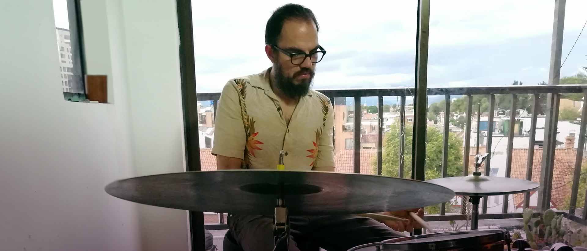 Hombre tocando bateria en un piso alto de un edificio