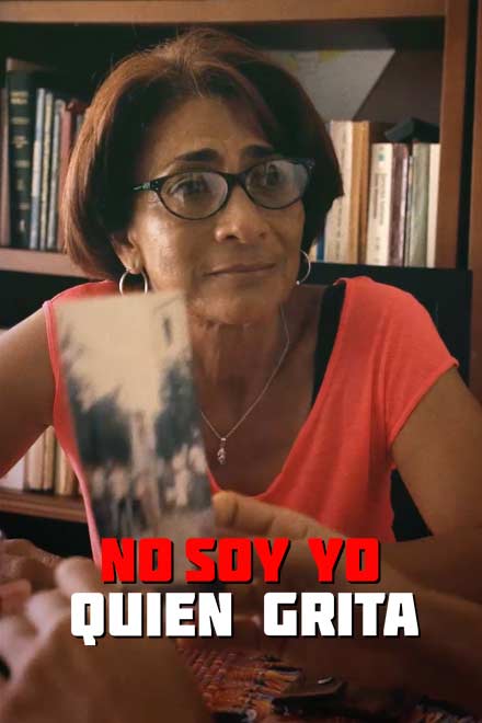 Mujer sentada observando a su hija mientras esta sostiene una foto en sus manos