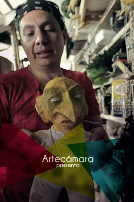 Artecámara presenta a un artista en su taller tomando a una marioneta o títere por sus brazos 