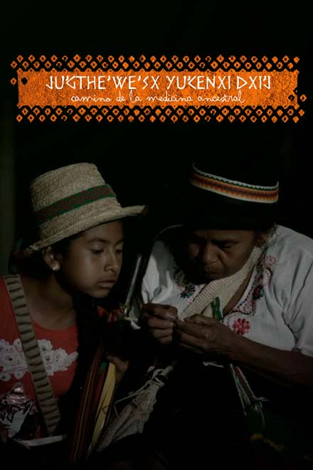 anciana indígena sentada mostrándole algo a una niña indígena