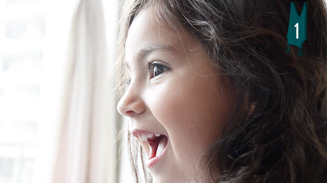Niña sorprendida mirando por la ventana