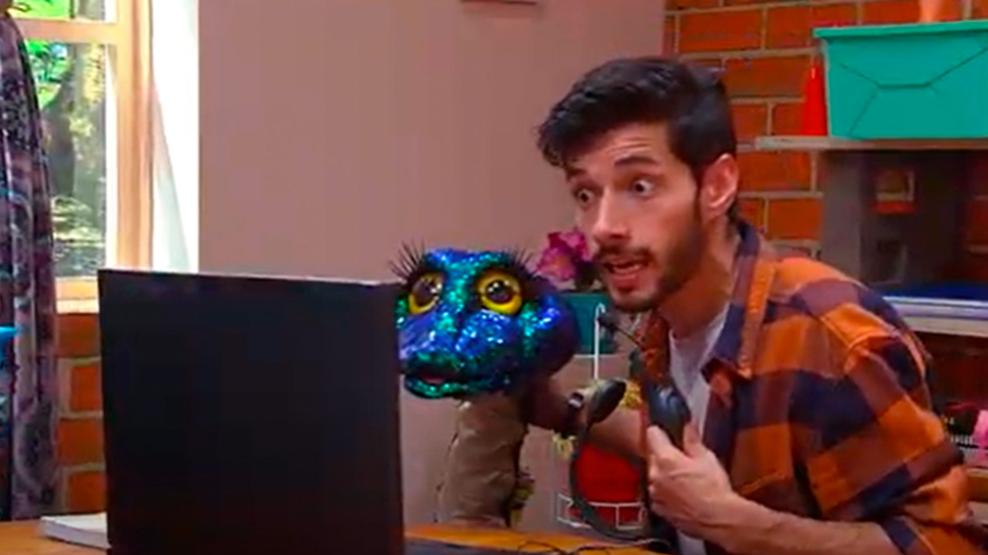 hombre y culebra de lentejuelas sorprendidos frente a una pantalla