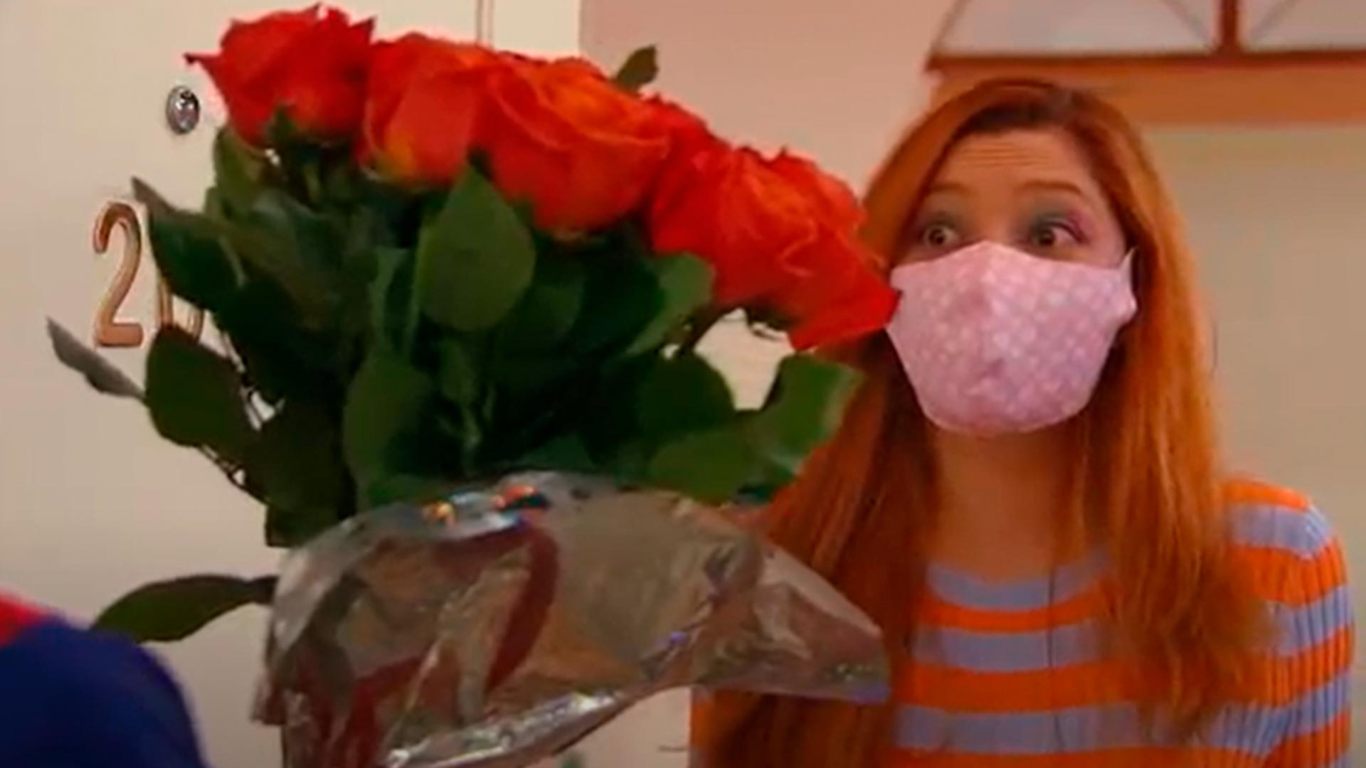 mujer con tapabocas recibiendo un ramo de rosas
