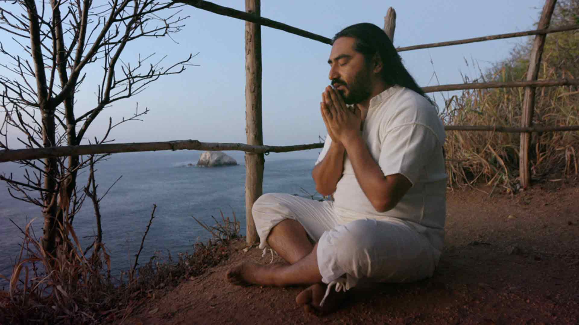 Indígena meditando en una montaña al frente del mar - Secreto ancestral