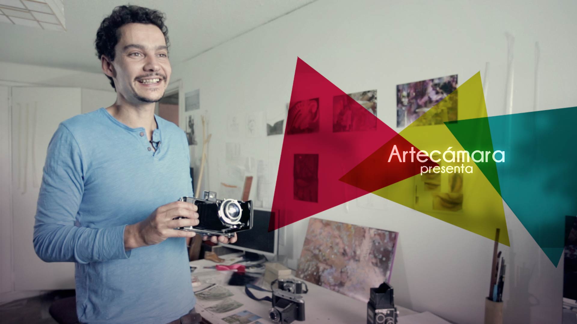 Artecámara presenta a un fotógrafo sosteniendo una cámaras en su apartamento