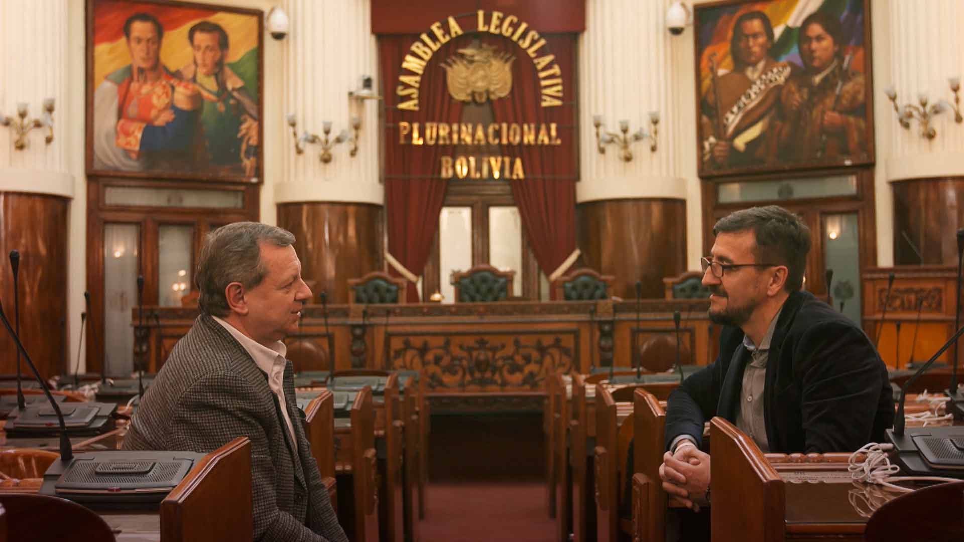 Mario Riorda conversa con otro hombre en la Asamblea Legislativa Plurinacional de Bolivia En el nombre del pueblo serie documental