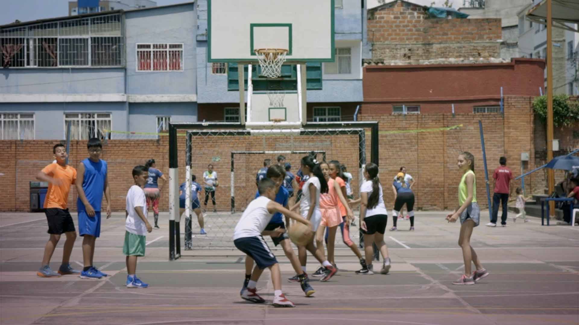 Niños y niñas jugando baloncesto es una cancha de un barrio - En sus marcas