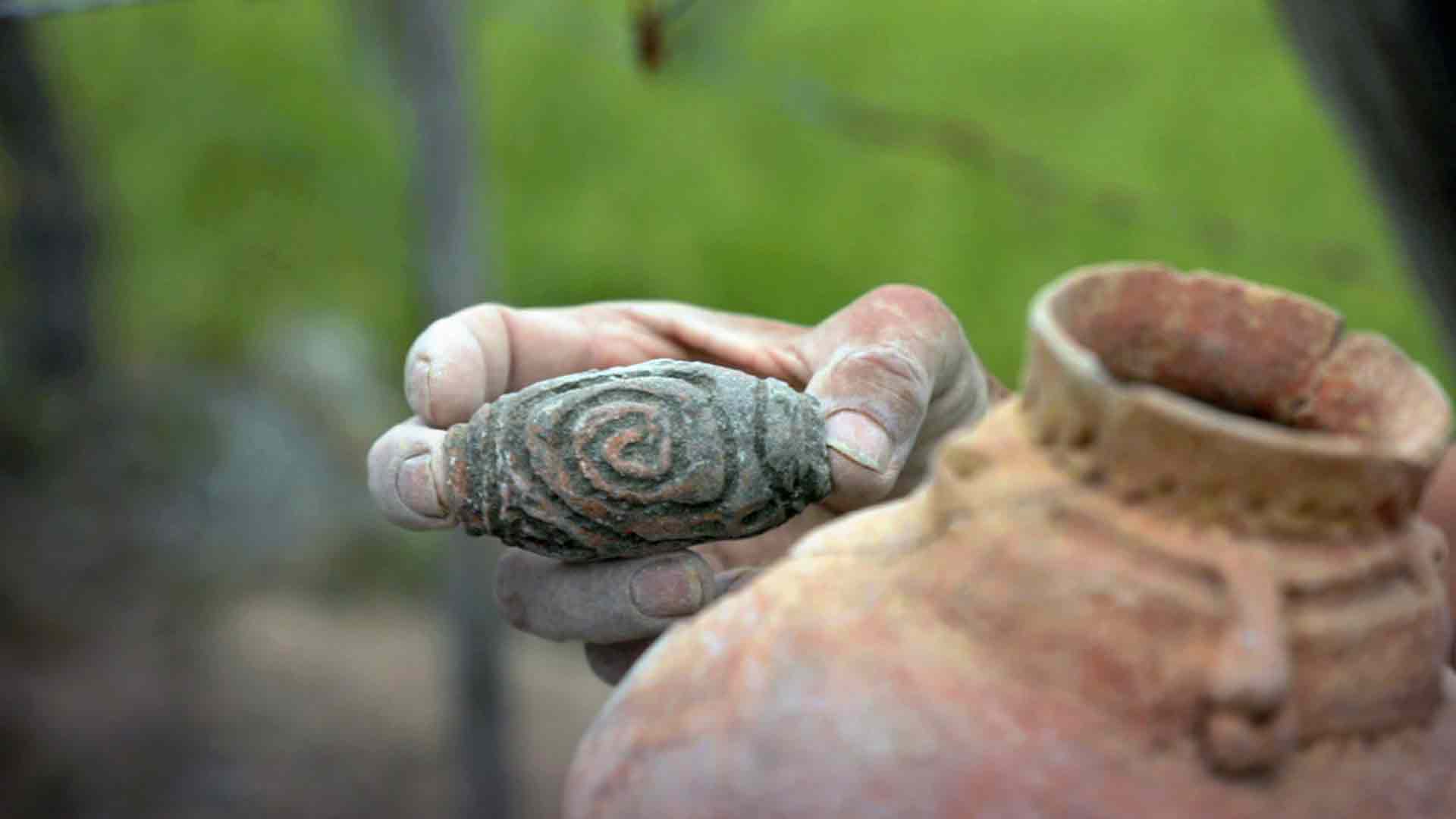 Mano sosteniendo una pieza arqueológica - Hijos de la Gaitana