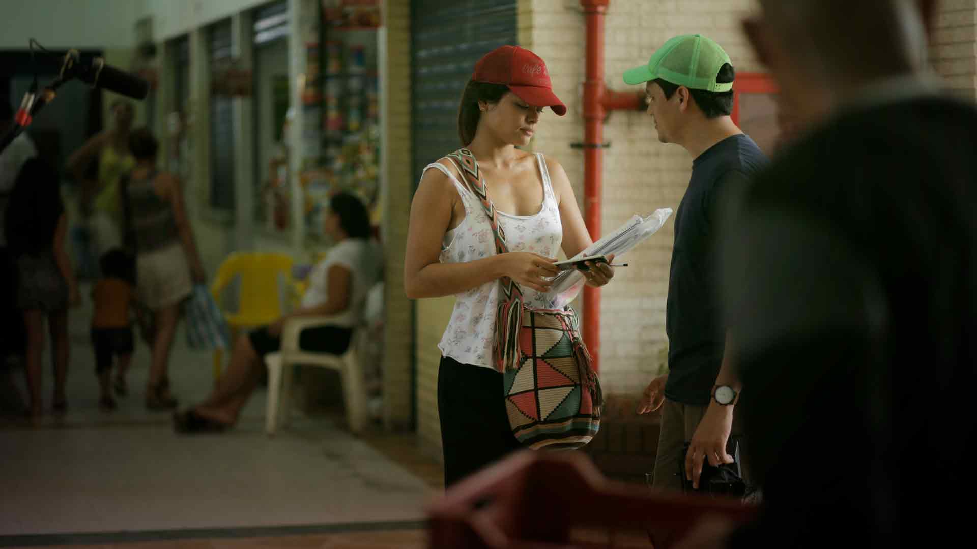 Hombre observando a mujer que sostiene celular y papeles en la mano - Mar de colores