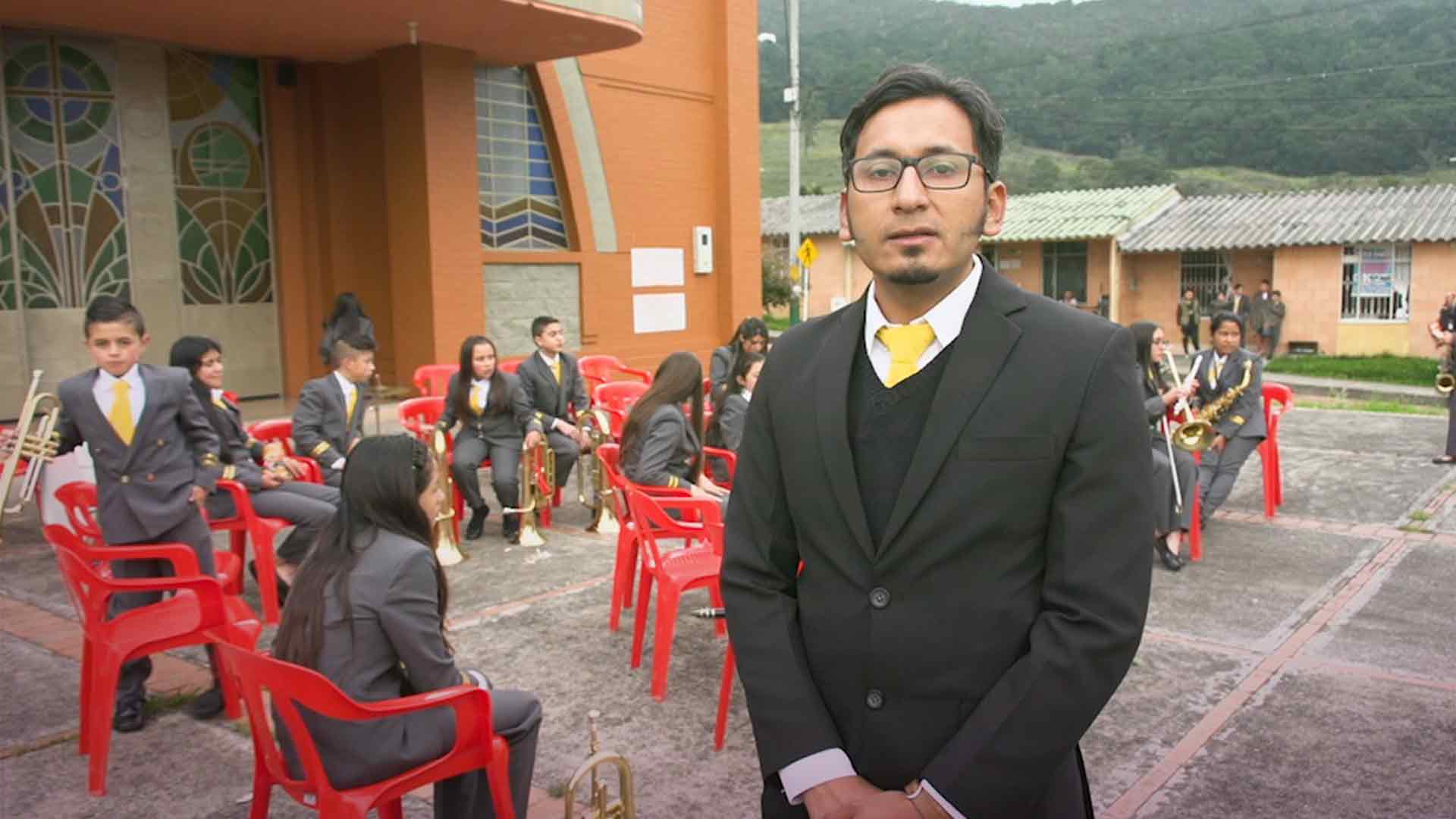 Director de grupo juvenil ensaya con su grupo al frente de una iglesia - Tan cerca y tan lejos