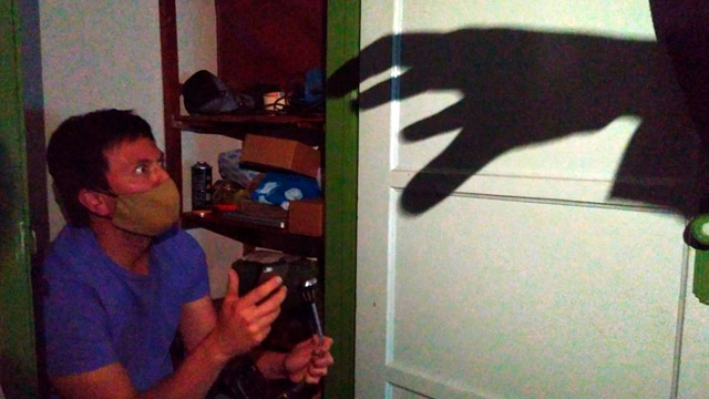 Un hombre asustado por una sombra en la pared de una mano fantasma