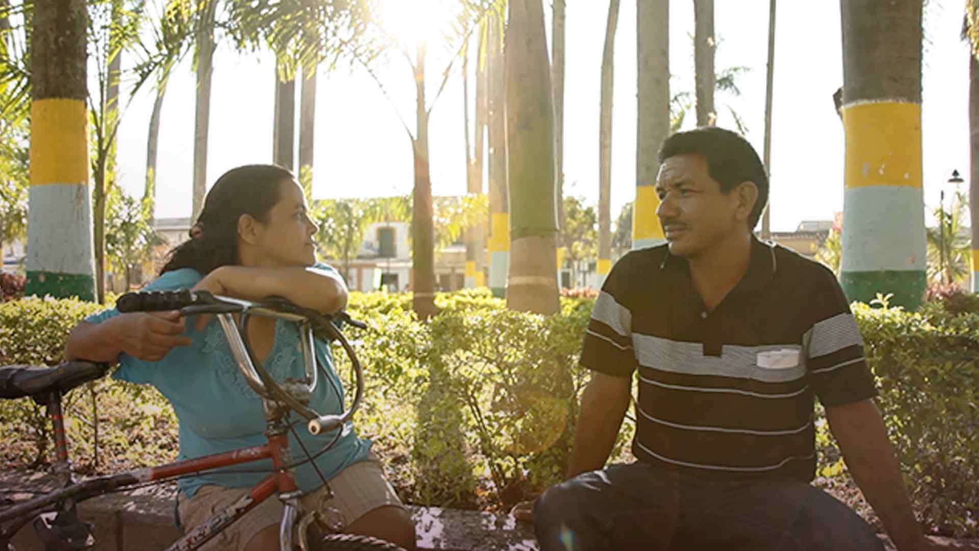 Un hombre y una mujer hablando junto a una cicla