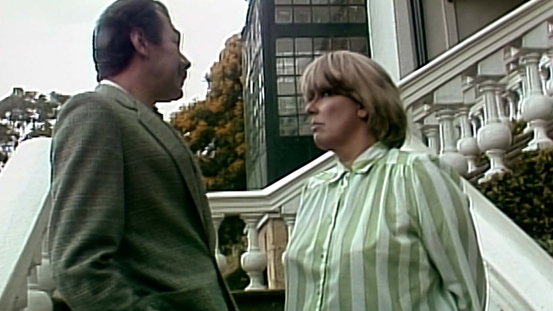 Narcisa hablando con un hombre en la fachada de la casa