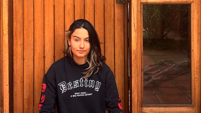 Mujer con cabello pintado delante de una puerta de madera
