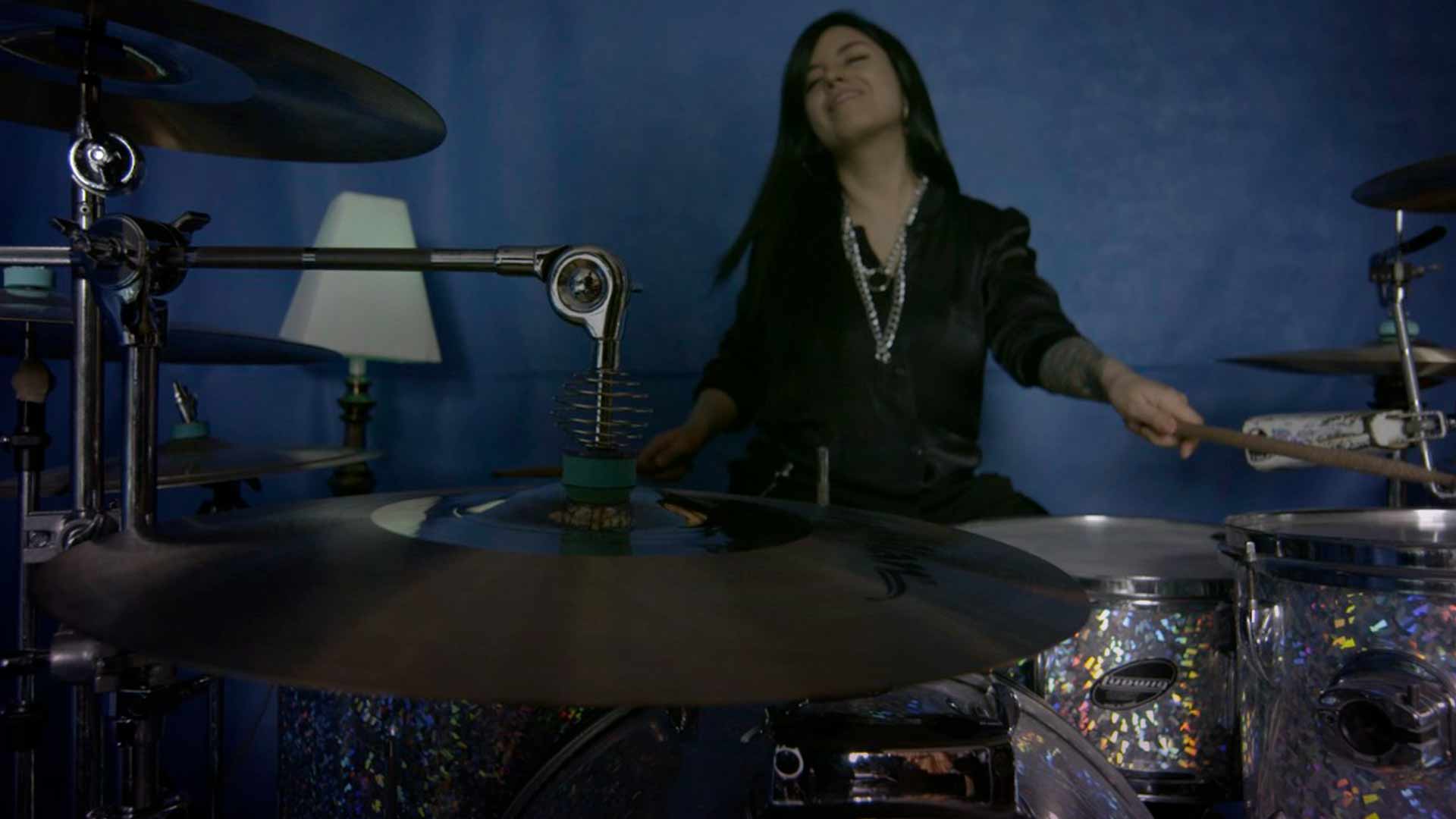 Mujer joven tocando batería en una casa 