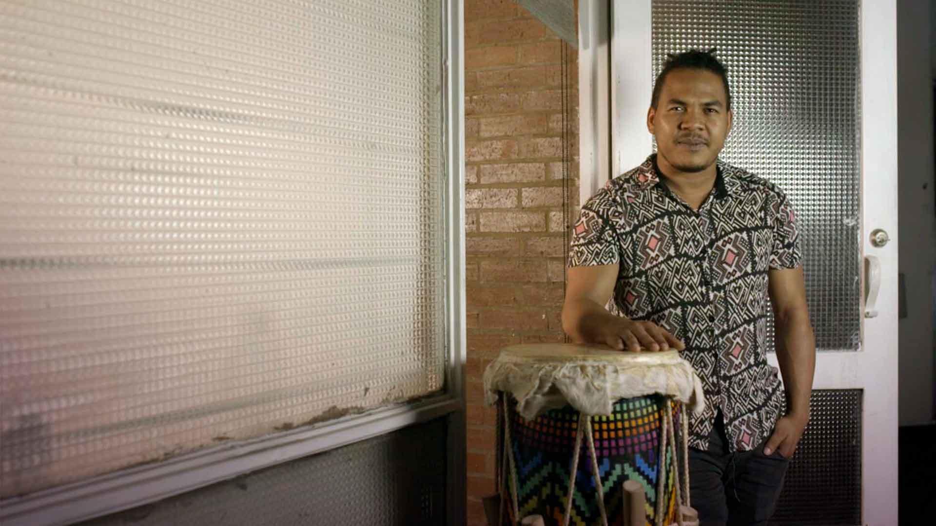 Hombre afro con una mano sobre un tambor 