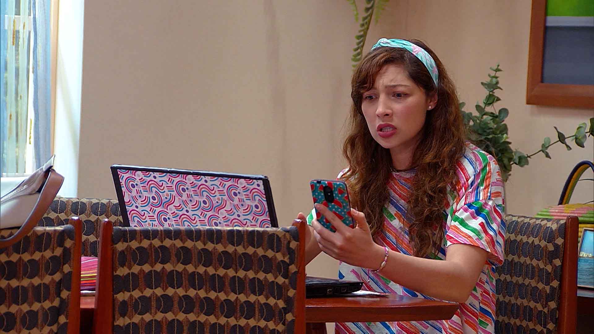 joven preocupada mirando el teléfono y su computador