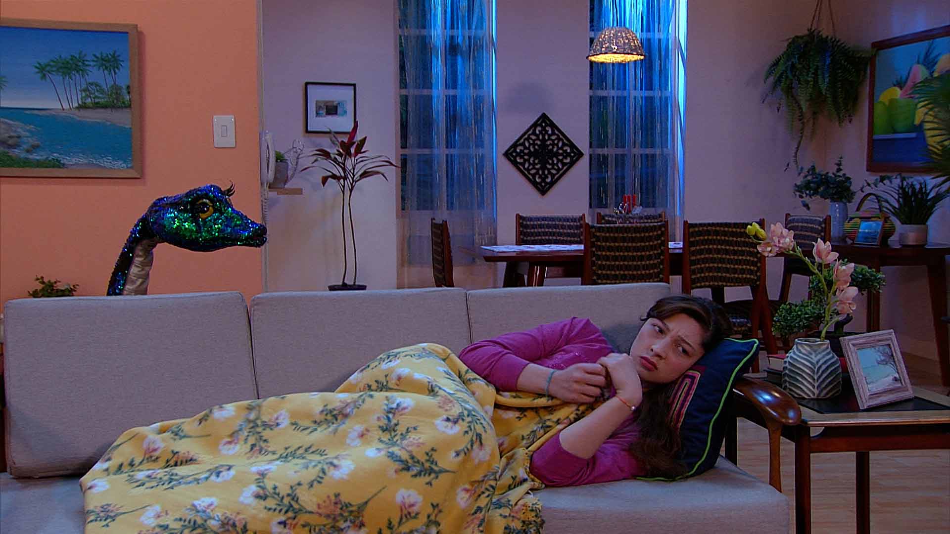 niña acostada en el sofá mientras la mira una serpiente