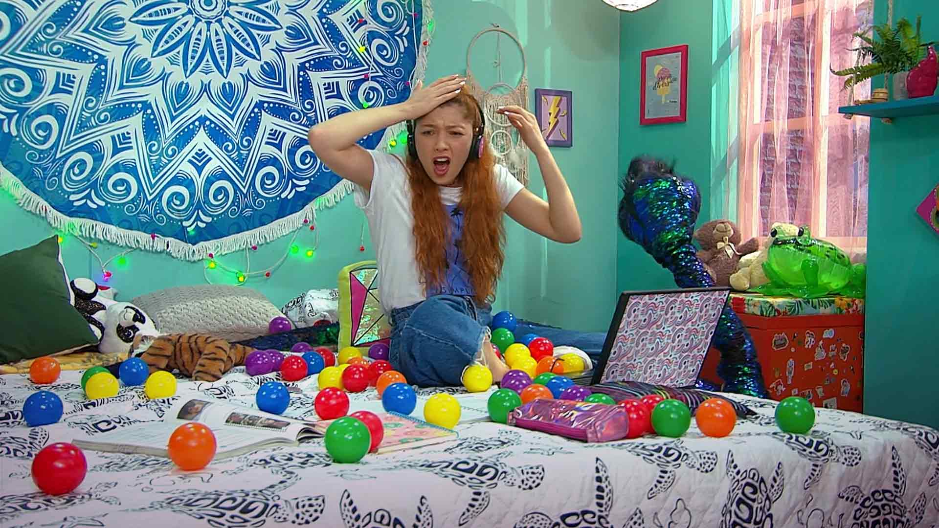 niña sobre una cama con un montón de pelotas de colores