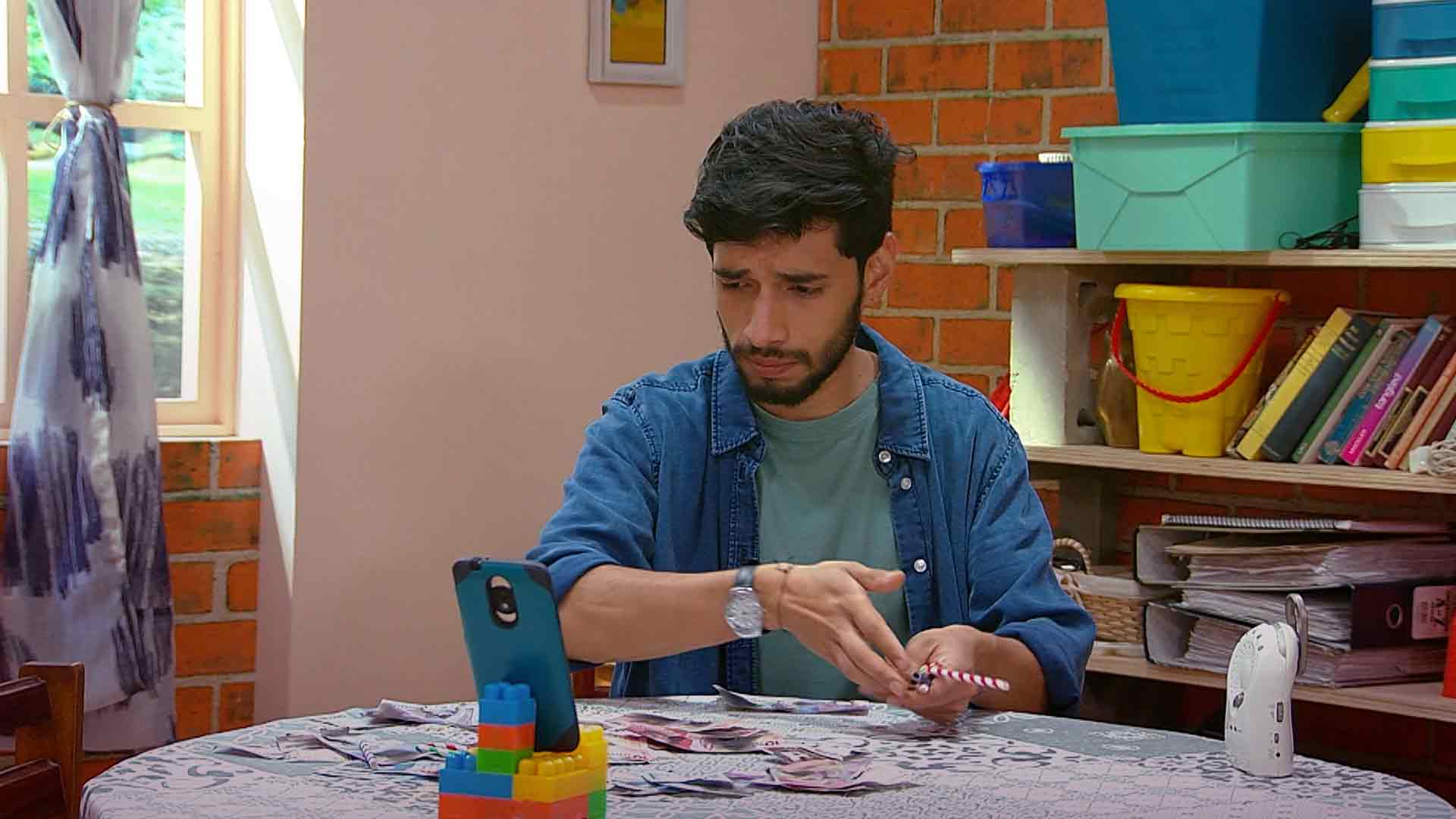 Hombre sentado mirando su celular puesto en un soporte