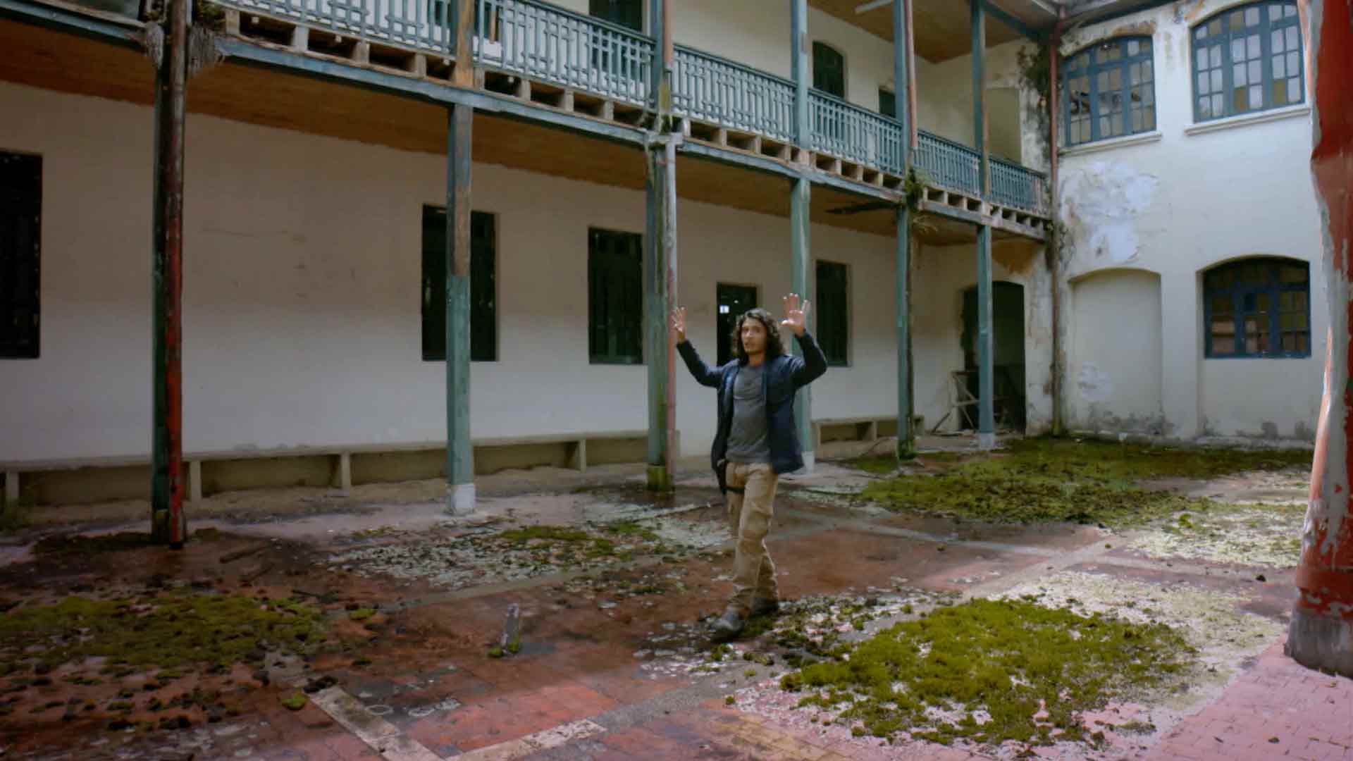 Joven caminando en el patio abandonado de un hospital