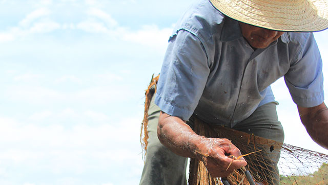 Abuelo pescador con sombrero y atarraya en sus manos 