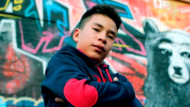 niño posando junto a un grafiti