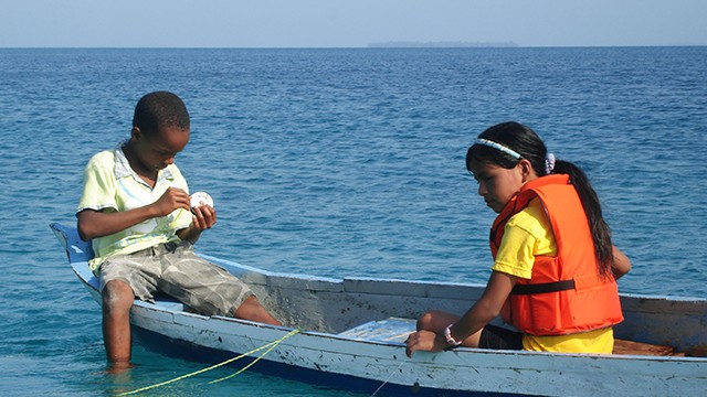 dos niños navegando sobre el mar en una lancha