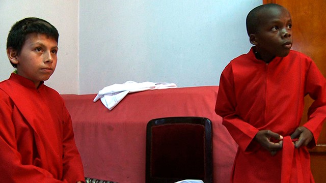 dos niños vestidos con túnicas rojas