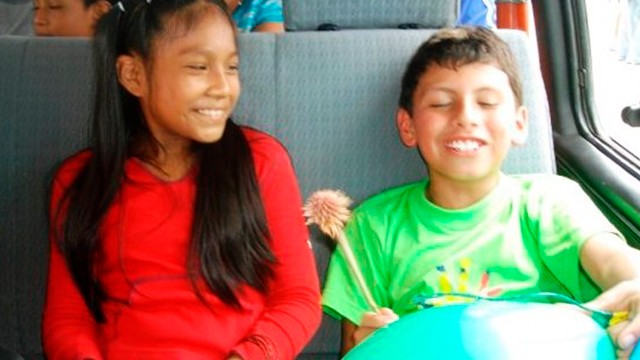 dos niños riéndose sentados en las sillas de un bus