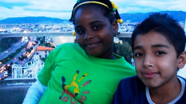 dos niños sonríen con la ciudad de fondo