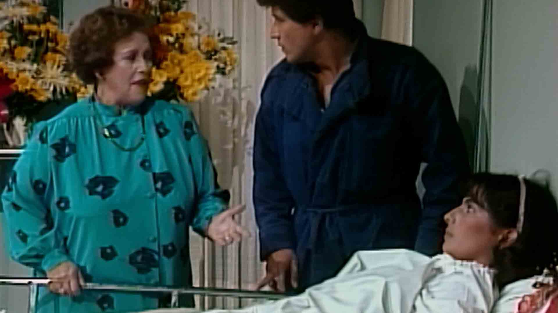 Miembros de la familia Olmedo hablan mientras una de ellos está acostada en la cama Los Cuervos serie ficción colombiana