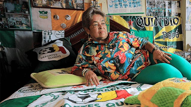 Abuela, mujer mayor en una cama rodeada de objetos del Deportes Quíndio