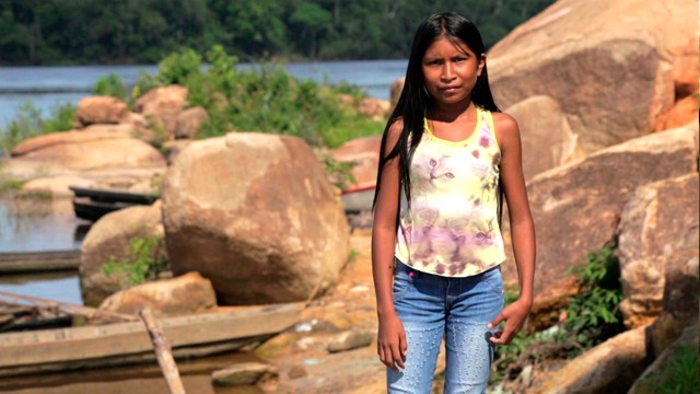 niña junto a un lago y rocas