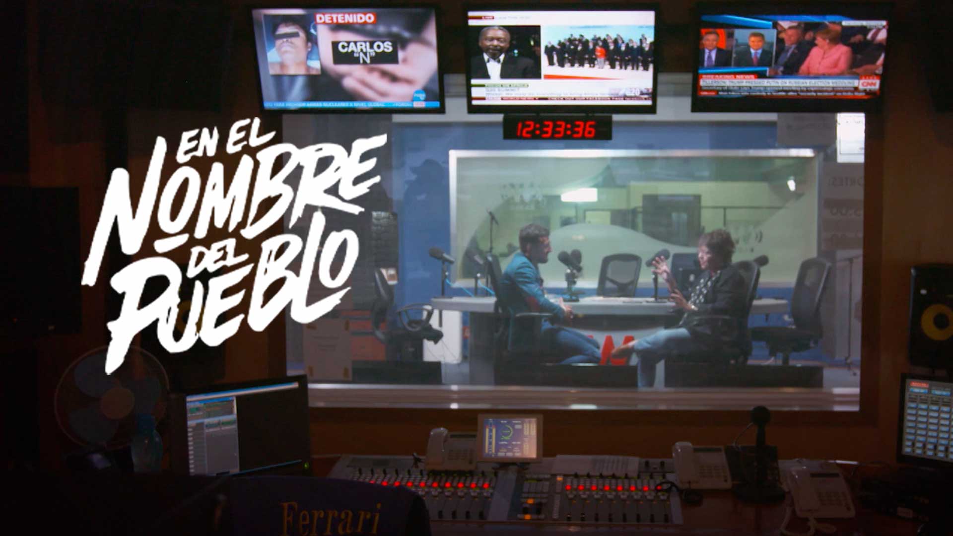 Master de cabina de radio y al fondo dos personas hablando 